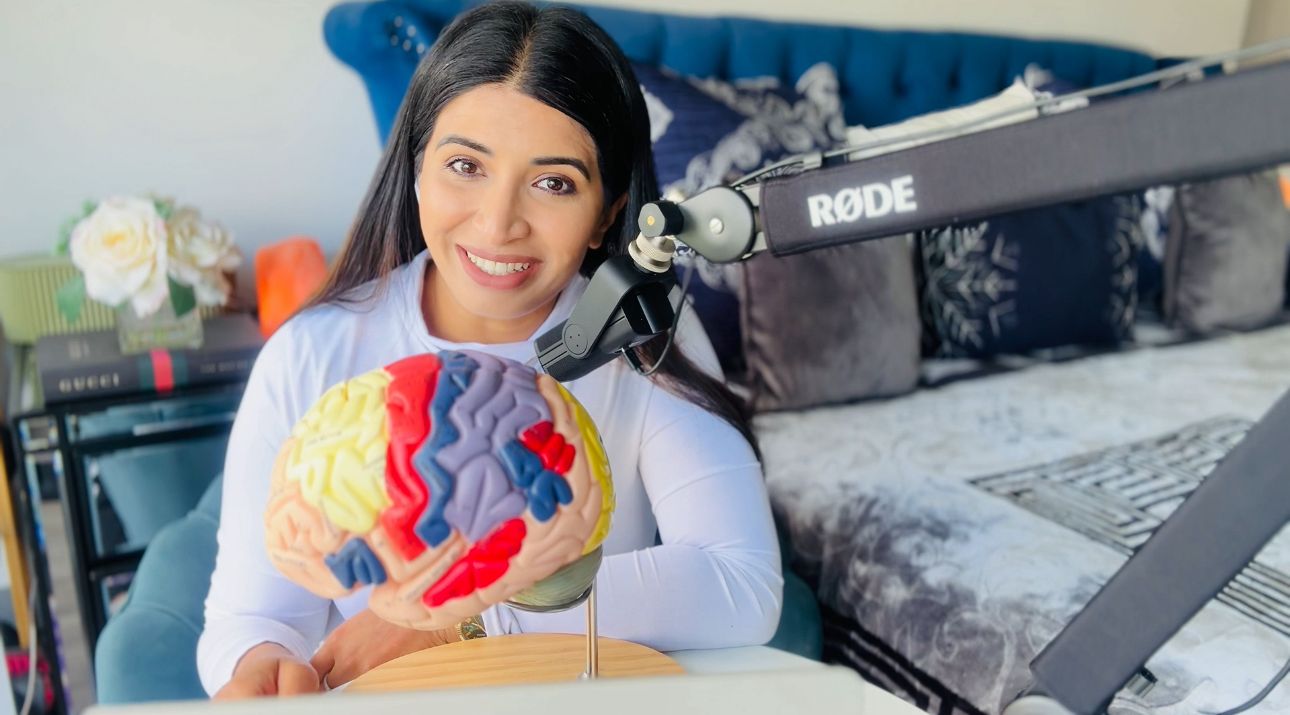Steny Lukose at her desk with a brain model